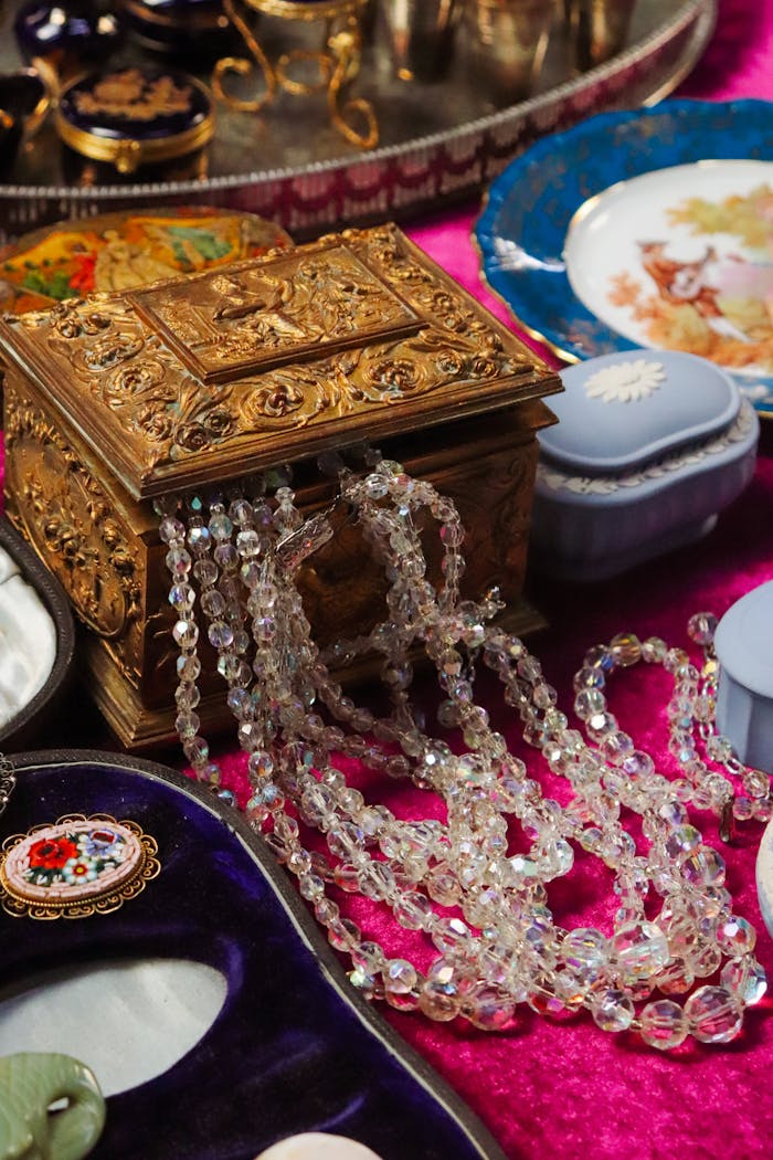 Antique jewelry box with crystal beads and decorative plates on velvet surface.